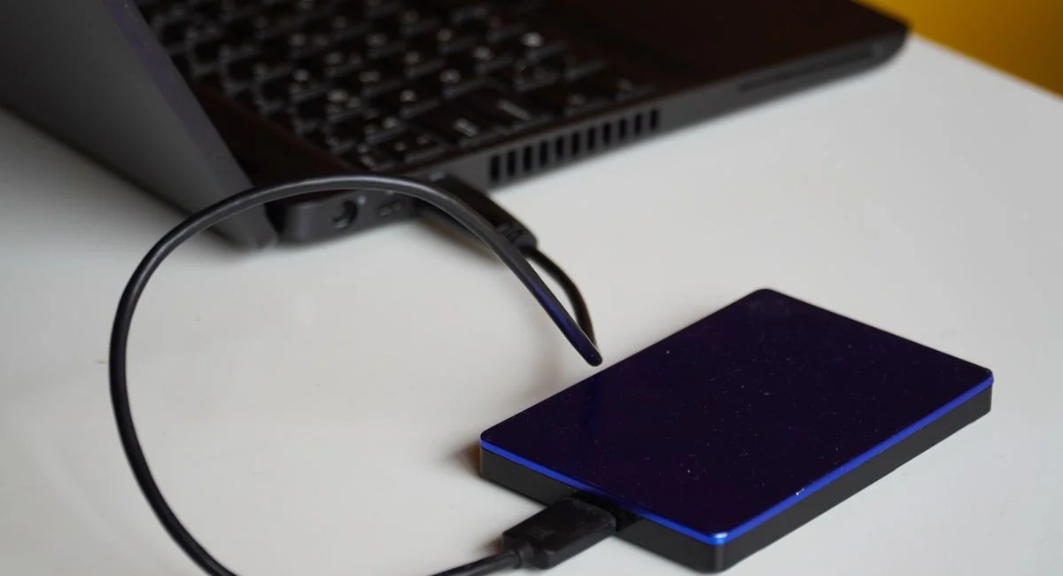 External hard drive connected to a laptop, showcasing portable storage solution.