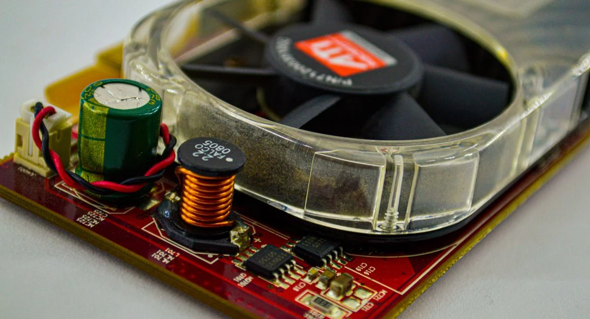 Detailed view of a cooling fan and capacitor on a computer circuit board, showcasing electronic components.