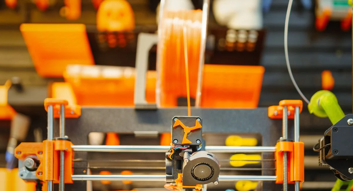 Close-up of an advanced 3D printer extruding filament in a workshop setting.