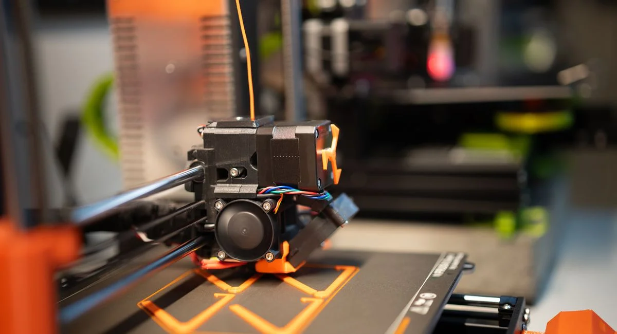 Detailed view of a 3D printer head in action creating a design.