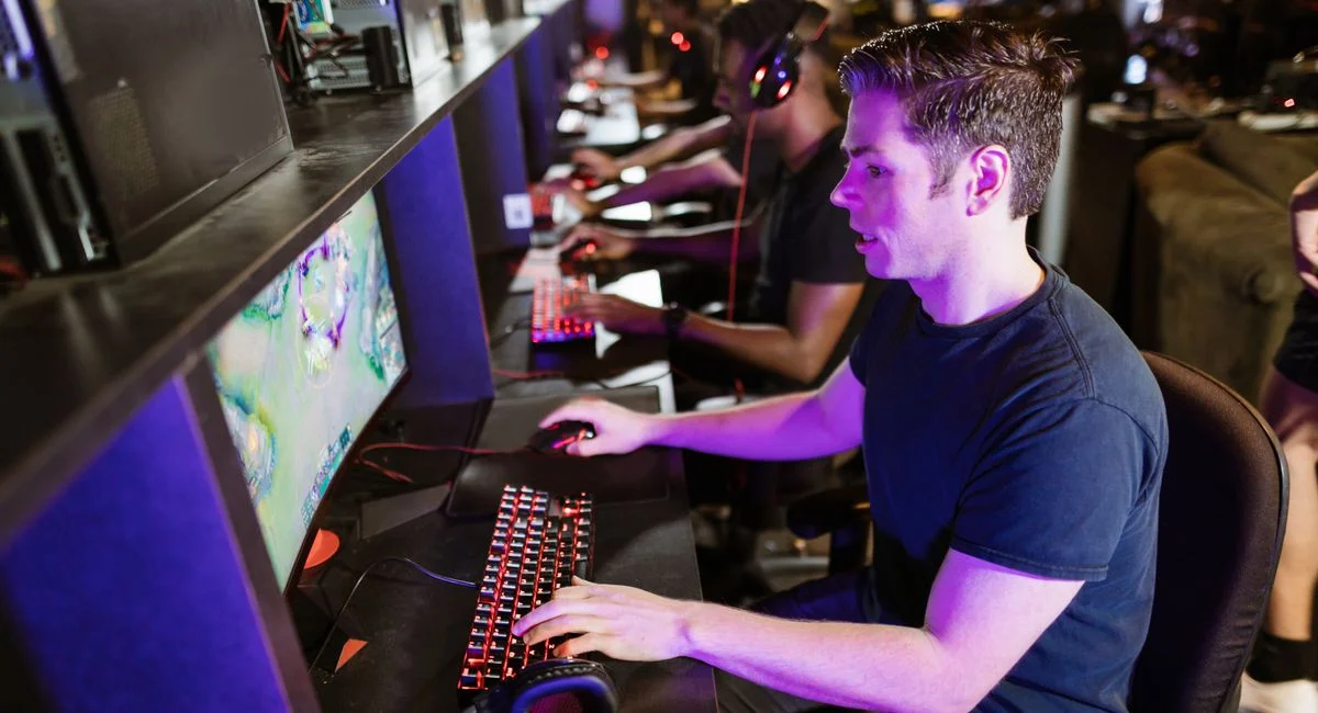A group of men playing video games in an arcade with glowing gaming setups.