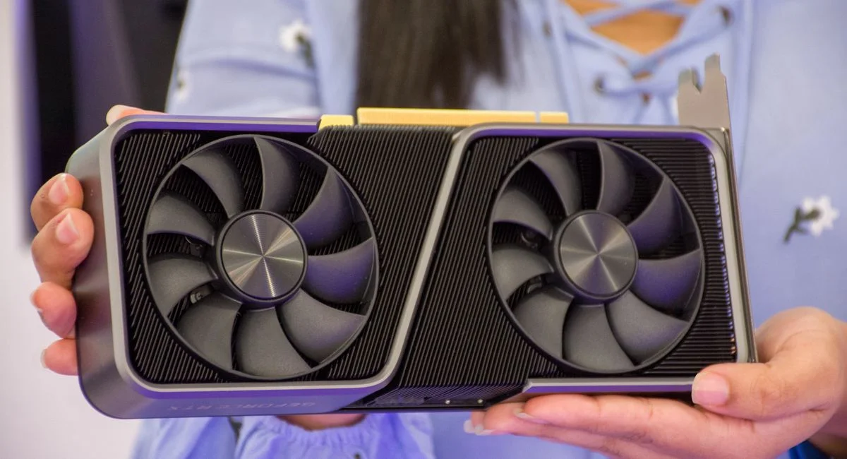 Detailed shot of hands holding a modern graphics card indoors.